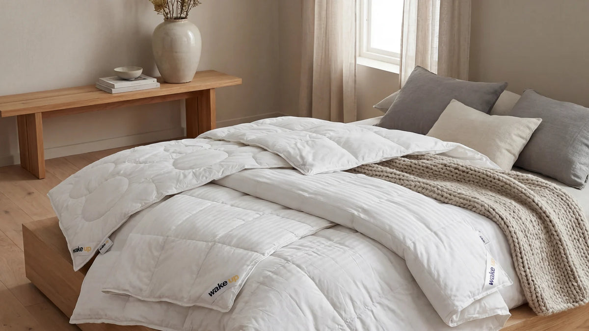 Opgemaakt bed met een gelaagd 4-seizoenen dekbed in een warme slaapkamer